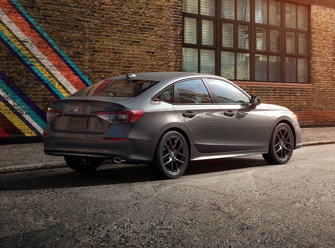 2027 Honda Civic Sedan Sport in Meteorite Gray Metallic rear three-quarter view parked on a city street (Compact Sedan)